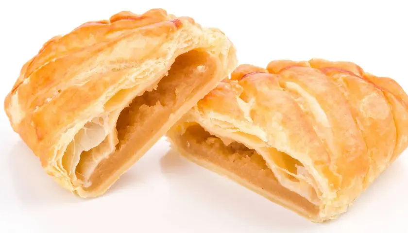 Pastelitos dorados y hojaldrados, cortados por la mitad, revelan un relleno dulce de ingredientes cabello de angel.