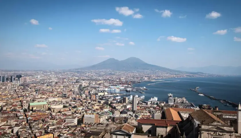 Panoramic view of Naples, Italy, with Mount Vesuvius in the background. Perfect for a Naples Italy itinerary, this vista captures the city's vibrant sprawl meeting the sea.