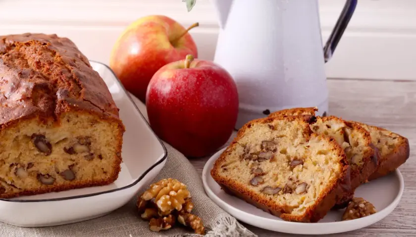 Un délicieux gâteau aux pommes et noix de grand-mère, avec des tranches présentées sur une assiette.