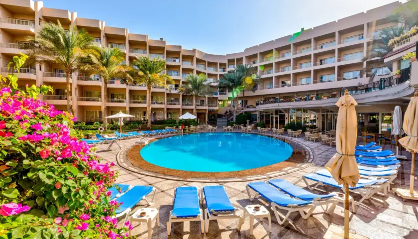 Basen hotelowy Beau Rivage z leżakami i palmami, otoczony budynkami hotelowymi.