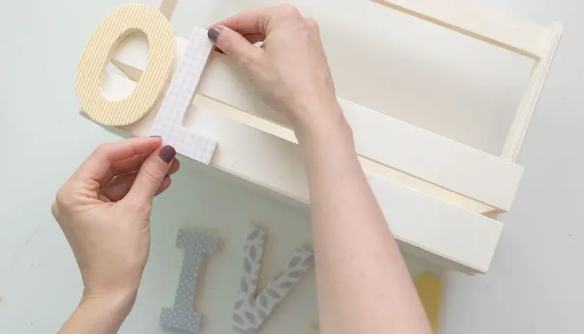 Manos decorando letras para manualidades de comunión, creando un detalle personal para un día especial.