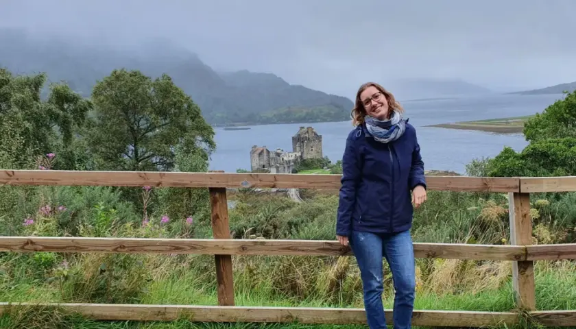 Frau vor schottischer Burg bei typischem Septemberwetter. Die Landschaft ist neblig, aber die Stimmung ist fröhlich.