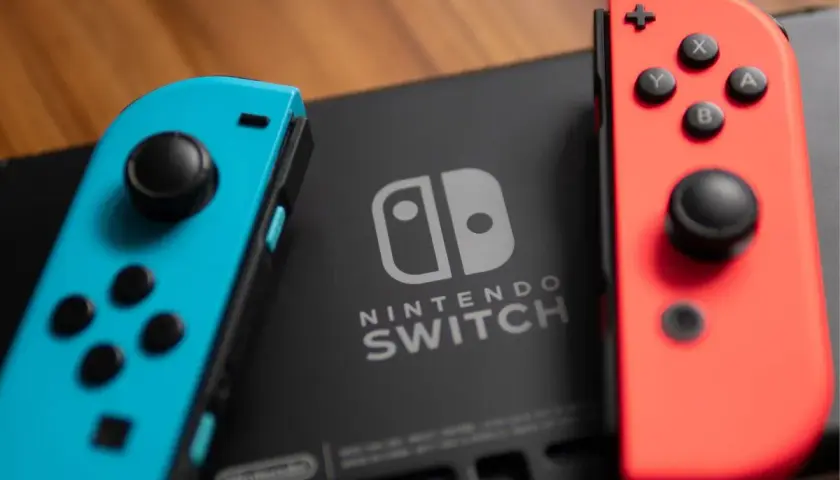 Dwa kontrolery Joy-Con, niebieski i czerwony, leżą obok konsoli Nintendo Switch. Idealne do odkrywania najlepszych gier na Nintendo Switch.