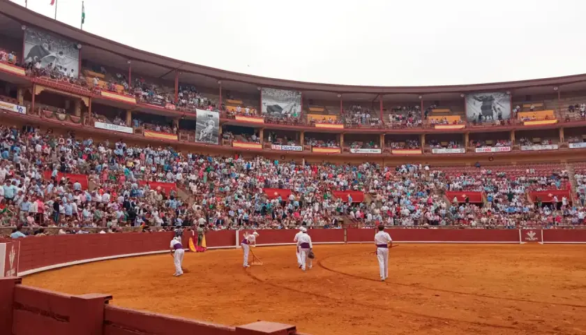 Toros en la grada seis. Multitud expectante en la plaza de toros, con toreros preparándose en la arena.