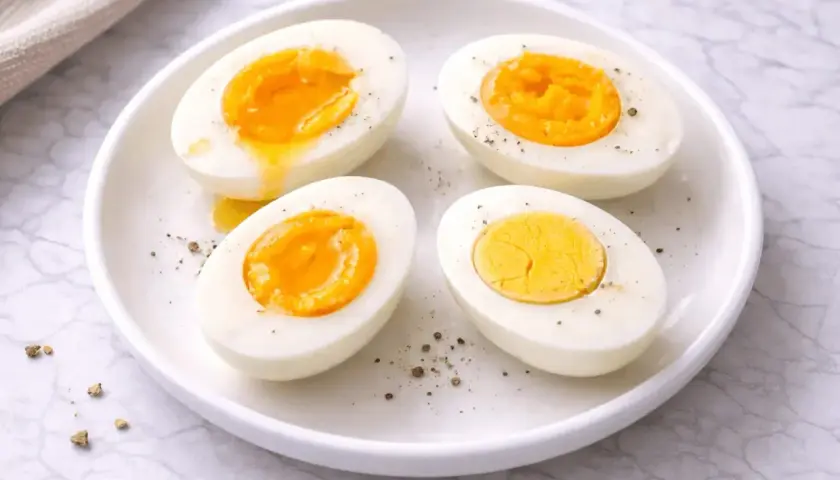 Quatre moitiés d'œufs durs sur une assiette blanche, certains avec un jaune coulant. Le temps d'un œuf parfait.