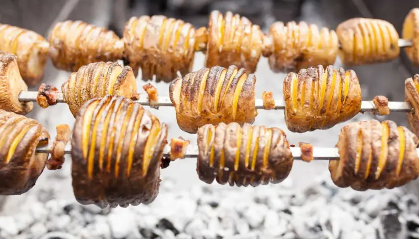 Pommes de terre coupées en accordéon, grillées à la broche sur des braises. Quelle pomme de terre barbecue !