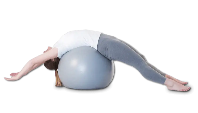 Une femme s'étire sur un ballon de gym, le dos cambré, dans une posture qui pourrait aider à corriger une cyphose.