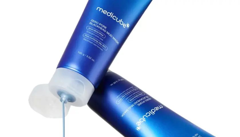 Två blå tuber med Medicube Zero Pore Blackhead Mud Mask. En tub har en öppen kork där masken droppar ut, en lösning för oljig hy orsak.