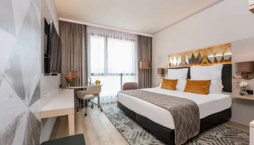 Nowoczesny pokój hotelowy z dużym łóżkiem, biurkiem i telewizorem.