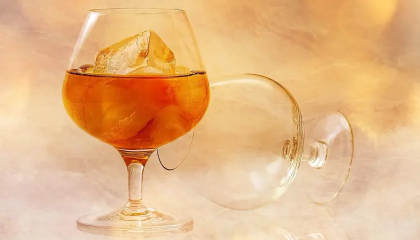Kieliszek z brandy i lodem, obok pusty, przewrócony kieliszek. Idealny sposób, jak pić brandy.