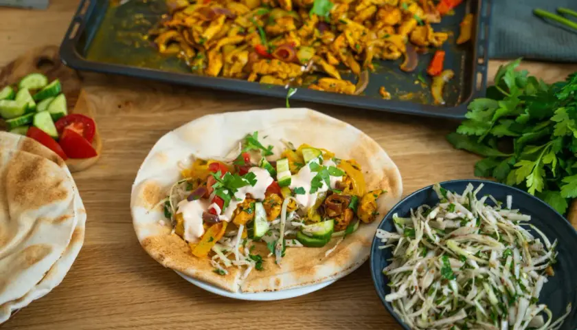 En läcker kyckling shawarma fylld med grönsaker och sås, serverad med pitabröd och en fräsch sallad.