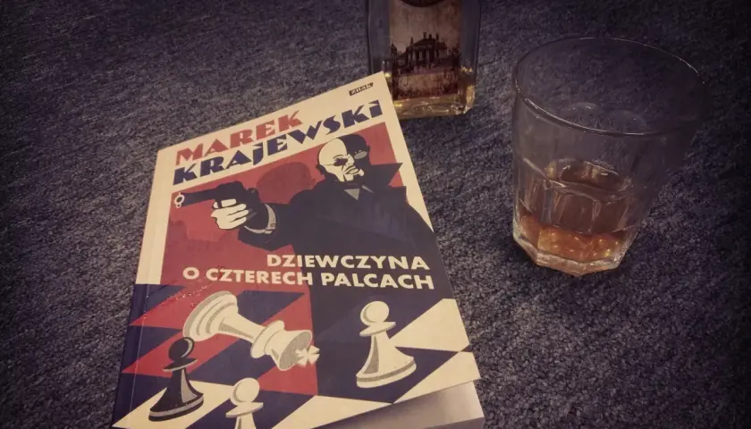 Książka "Dziewczyna o czterech palcach" Marka Krajewskiego, idealna na wieczór z whisky. Kolejność czytania jego powieści jest ważna dla pełnego odbioru.