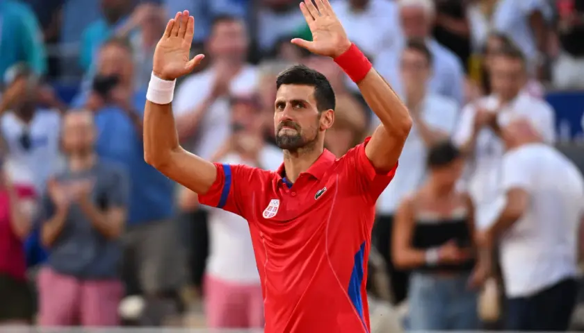 Novak Djoković w czerwonej koszulce z podniesionymi rękami, pozdrawia publiczność po zwycięstwie w turnieju WTA 500.