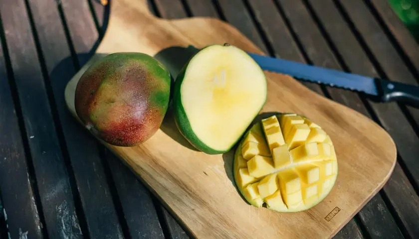 Süße, saftige Mangostücke auf einem Holztisch. Die Frage "ist mango gesund" wird durch diese leckere Frucht beantwortet.