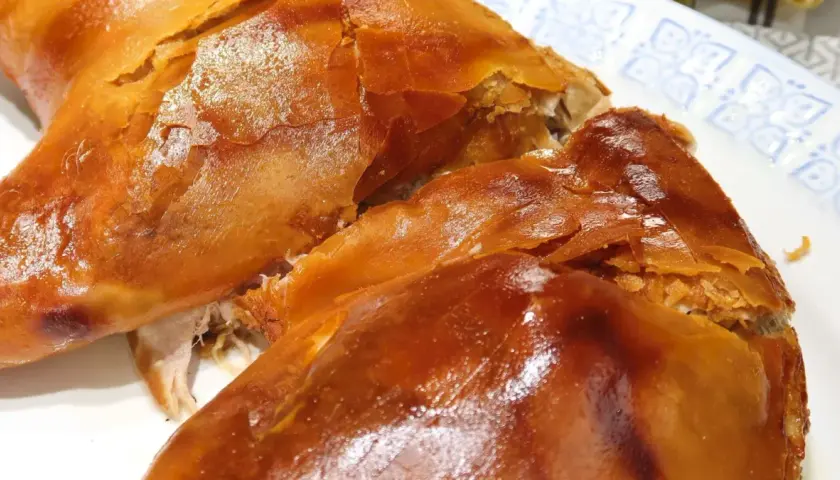 Un crujiente cochinillo al horno, con piel dorada y carne jugosa, listo para ser disfrutado.