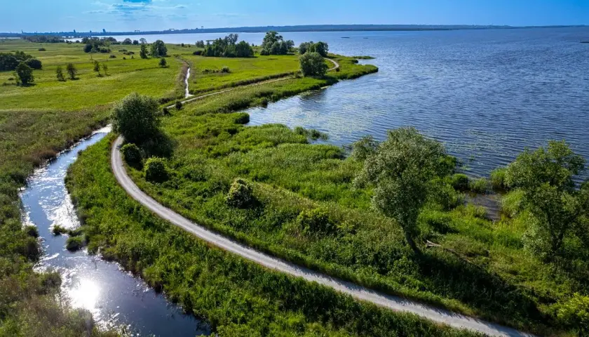 Malownicze trasy rowerowe Szczecin wiodące wzdłuż rzeki i jeziora, otoczone bujną zielenią.