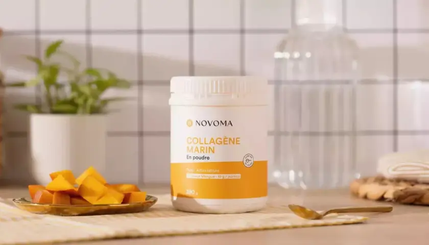 Un pot de cure de collagène marin en poudre saveur mangue, accompagné de dés de mangue fraîche.