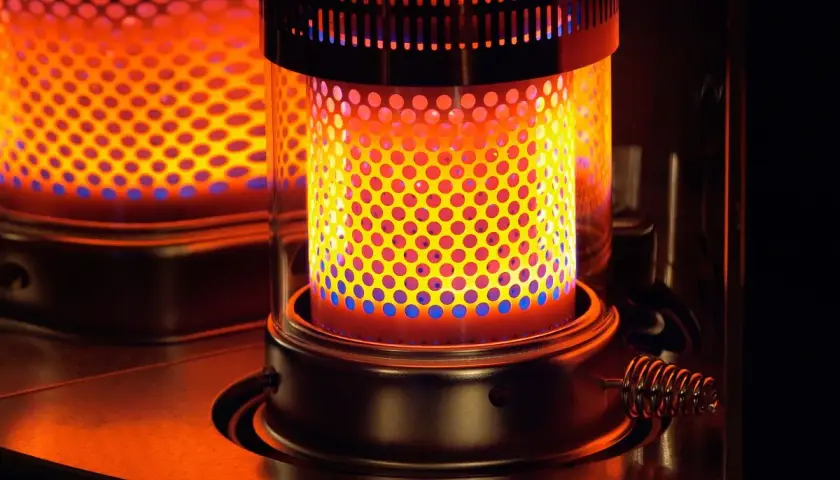 Estufa de parafina encendida, con llama naranja y azul. Considera sus pros y contras para calentar tu hogar.