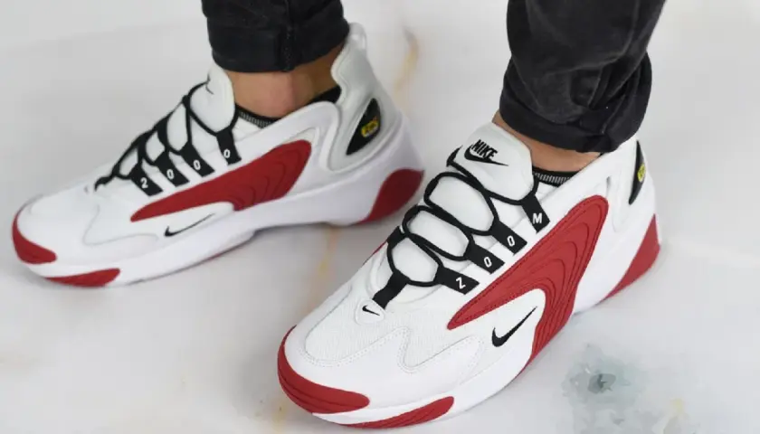 Białe buty Nike z czerwonymi akcentami i czarnymi sznurówkami. Numer "2000" na sznurówkach nawiązuje do historii marki Nike.
