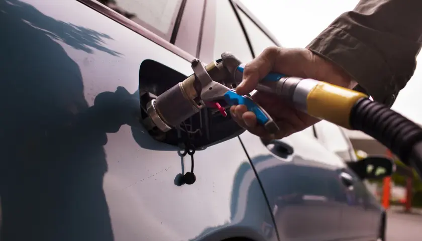Rifornimento GPL. Se la bombola gpl scaduta posso circolare a benzina? La mano inserisce la pistola di rifornimento nel serbatoio dell'auto.