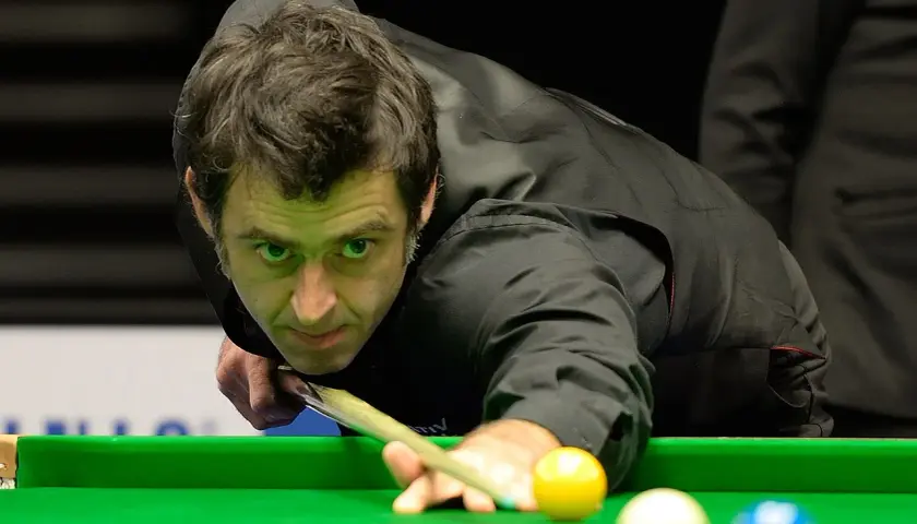Ronnie O'Sullivan w akcji, skupiony na grze w snookera. Jego sportowa pasja widoczna w każdym ruchu.