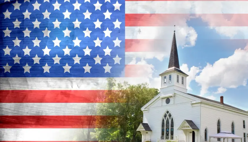 Amerikanische Flagge über einer weißen Kirche, die die Präsenz von Katholiken in den USA symbolisiert.