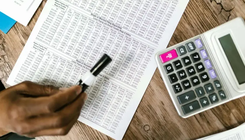 Tabela z danymi finansowymi, kalkulator i ręka analizująca układ rodzajowy kosztów.