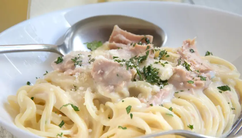 Cremige Nudeln mit Thunfisch, garniert mit Petersilie und Parmesan. Ein köstliches Gericht, das Lust auf mehr macht.