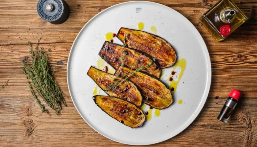 Gegrillte Auberginenscheiben als Antipasti, beträufelt mit Olivenöl und Balsamico, garniert mit Thymian.