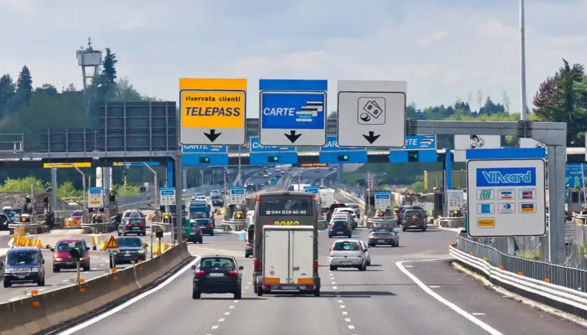 Autostrada we Włoszech z bramkami opłat, znakami Telepass i Carte, oraz samochodami w ruchu.