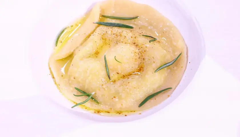 Ravioli z płynnym żółtkiem, ozdobione rozmarynem i przyprawami, danie godne MasterChefa.