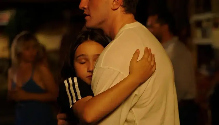 Un abbraccio intenso, una bambina si stringe a un uomo. Una scena che fa pensare a un momento di conforto, quasi una spiegazione dopo il sole.