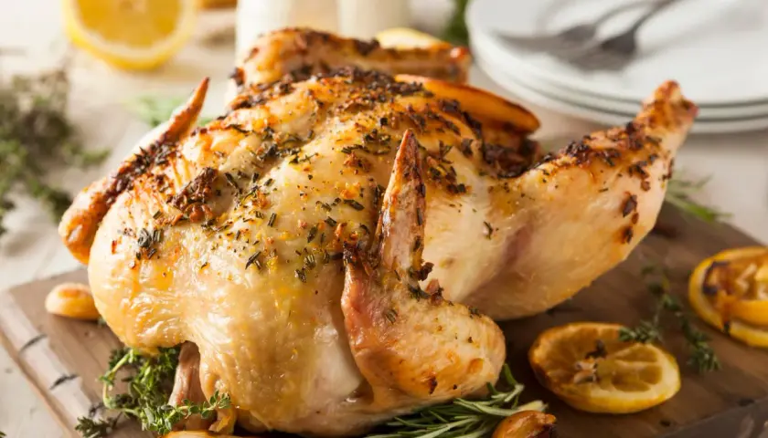 Un poulet entier au barbecue, doré et savoureux, garni d'herbes et de quartiers de citron grillés. Un délice pour les papilles !