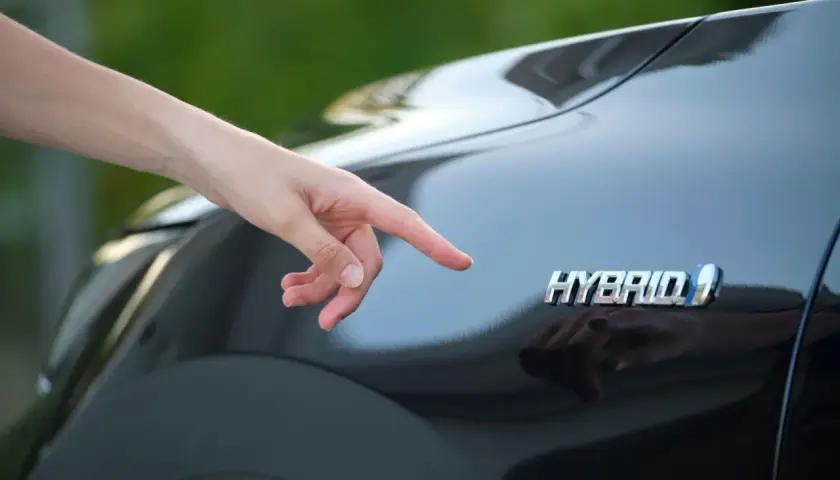 Dito il logo "Hybrid" su una Toyota Yaris. Si pensa al costo del bollo per un'auto ibrida.