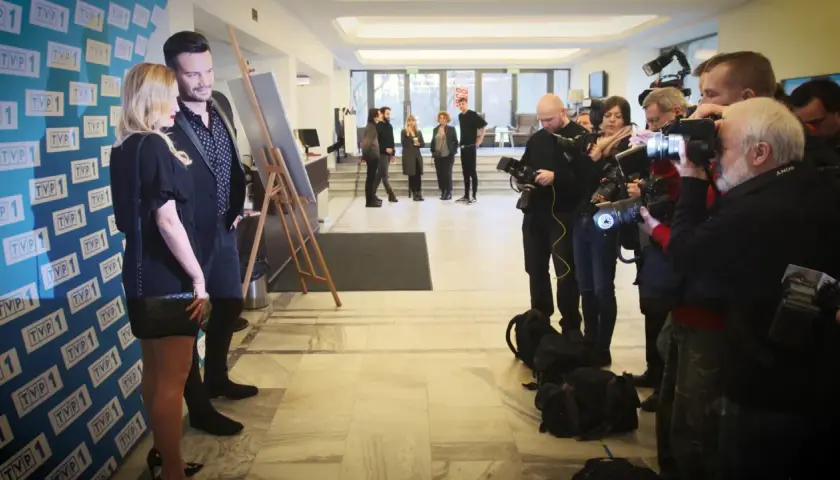 Sylwia Juszczuk z mężami pozuje do zdjęć, otoczona przez fotoreporterów.
