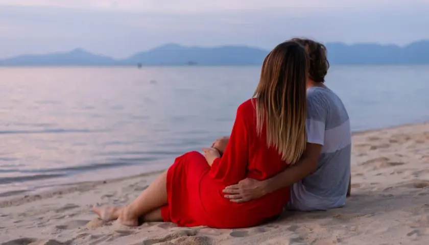 Para dla dwojga siedzi na plaży, patrząc na morze. To fajne miejsce nad morzem dla dwojga, idealne na romantyczny wieczór.
