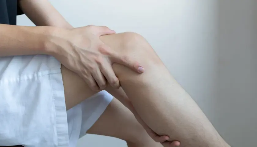 Dłoń uciska udo, sugerując ból lub dyskomfort, który może być jednym z niedobór potasu objawy neurologiczne.