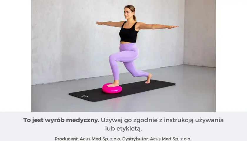 Kobieta wykonuje ćwiczenia równowagi na różowej poduszce sensorycznej, stojąc na macie.