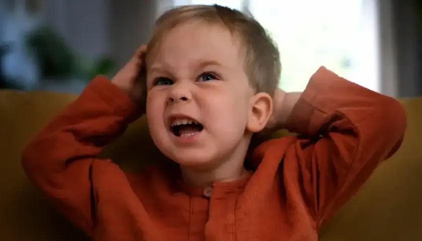Niño de 3 años con expresión de frustración, agarrándose la cabeza. ¡Los terribles 3 años en todo su esplendor!