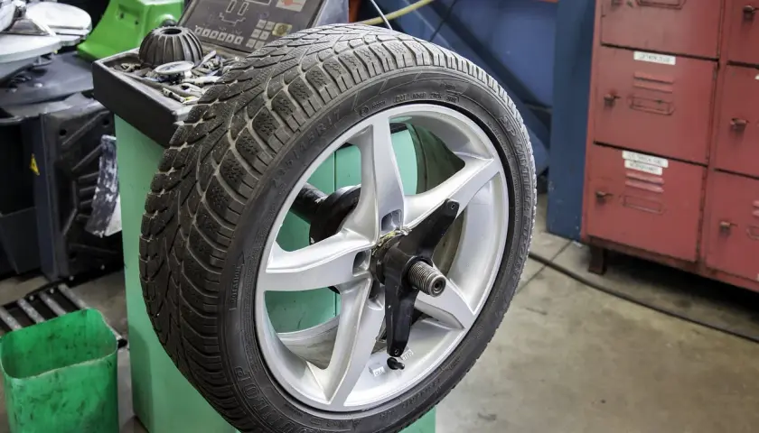 Koło 235/45 R18 na wyważarce. Zastanawiasz się, jakie ciśnienie w oponach 225/45 R18? Sprawdź instrukcję pojazdu.