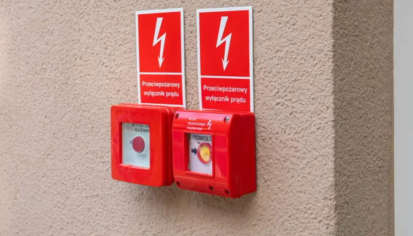 Dwa czerwone przyciski awaryjne z tabliczkami "Przeciwpożarowy wyłącznik prądu". Zgodnie z przepisami, są kluczowe dla bezpieczeństwa.