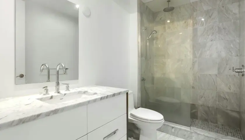 Modernt badrum med marmor, dusch och toalett. Enkel design som visar att det går att renovera badrum billigt med stil.