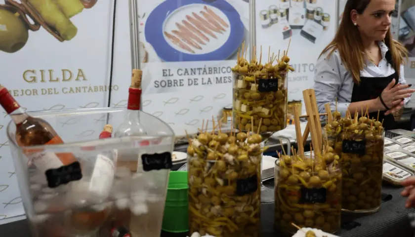 En la feria de la anchoa en Santoña, se exhiben gildas y aceitunas marinadas. Botellas de vino esperan ser servidas.