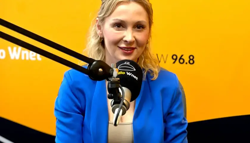 Joanna Miziołek, w wieku około 40 lat, w niebieskiej marynarce, przed mikrofonem Radia Wnet.
