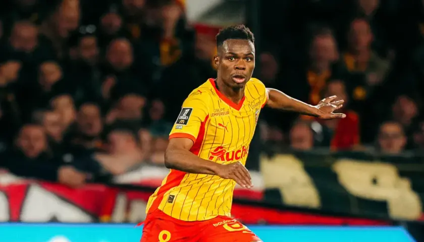 Piłkarz RC Lens w żółto-czerwonej koszulce biegnie po boisku, gotowy do akcji przeciwko Stade Rennais.
