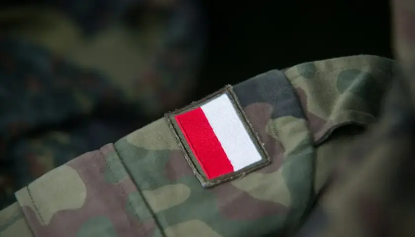 Fragment munduru wojskowego w kamuflażu z naszywką z polską flagą. Różne rodzaje mundurów wojskowych mają swoje unikalne oznaczenia.