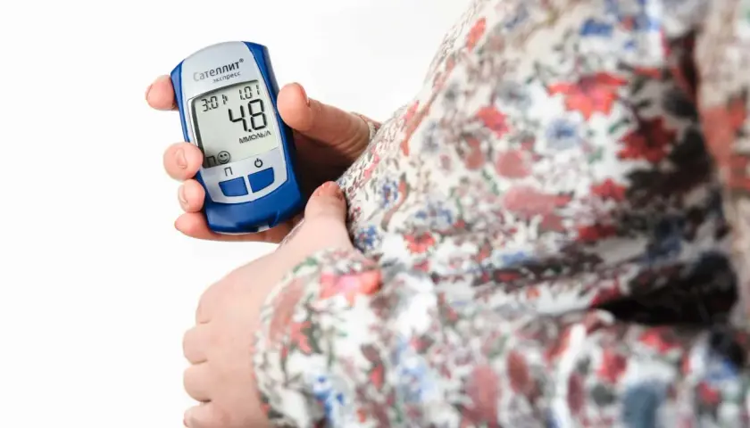 Gravid kvinna kontrollerar sitt blodsocker med en glukosmätare. En viktig del av att hantera graviditetsdiabetes.
