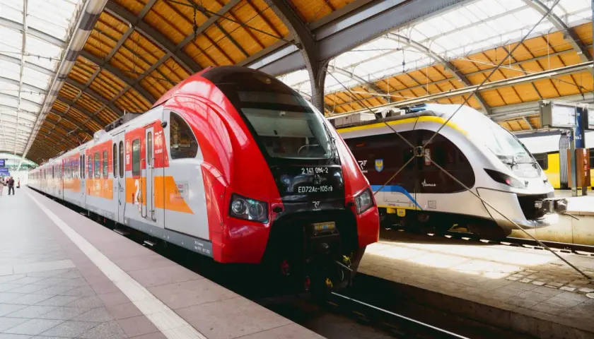 Dwa nowoczesne pociągi stojące na peronie. Czerwony pociąg Polregio i biało-niebieski Impuls, gotowe do podróży. Połączenie kolejowe Wrocław.