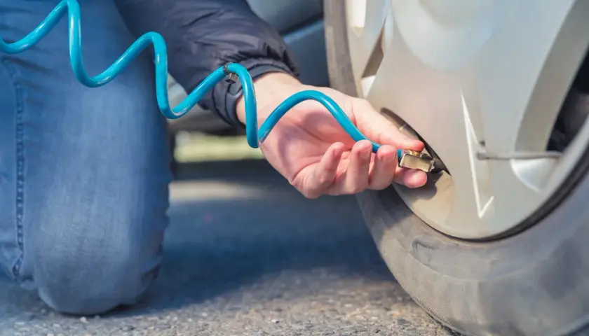 Persona infla ruedas con nitrógeno usando una manguera azul.