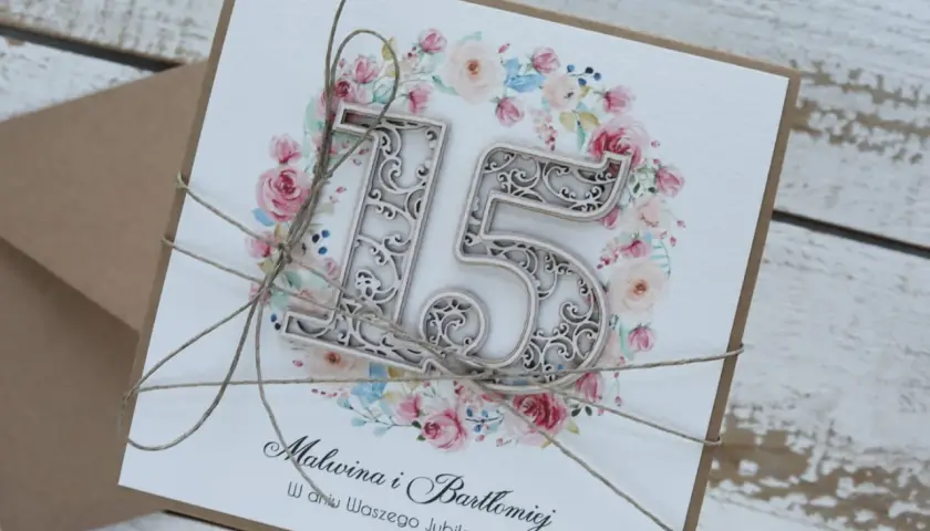 Elegancka kartka z okazji 15 rocznicy ślubu Malwiny i Bartłomieja, ozdobiona kwiatowym wianuszkiem i ażurową cyfrą "15".